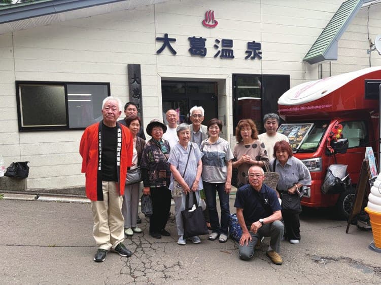 大葛温泉の前で地域の皆さんと記念撮影する佐藤和幸